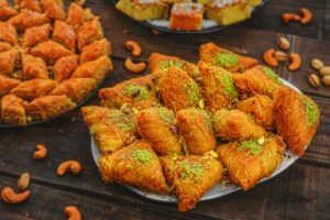 A close-up of traditional Turkish sweets with pistachios on a wooden table.